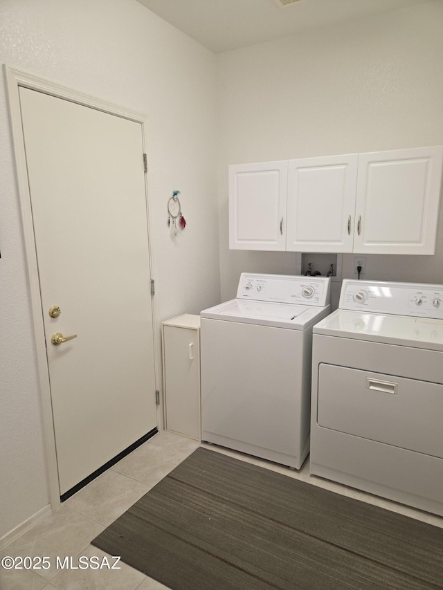 clothes washing area with cabinet space, washer and clothes dryer, and light tile patterned flooring