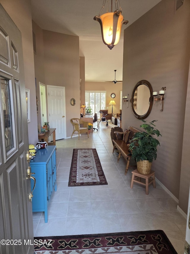 foyer entrance featuring light tile patterned floors, a high ceiling, visible vents, and baseboards