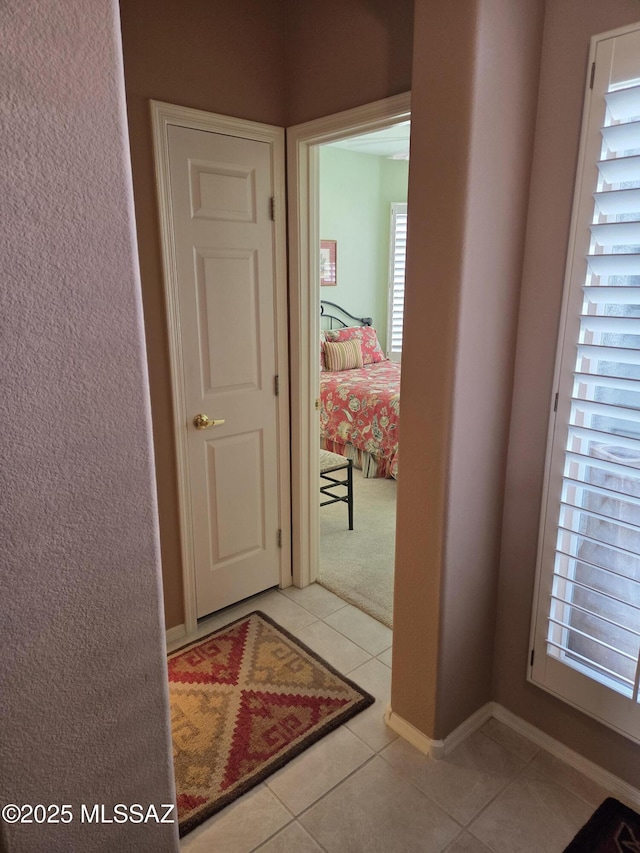 corridor featuring tile patterned flooring and baseboards