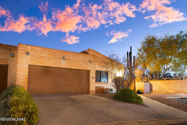 view of front of house featuring an attached garage, central AC, and concrete driveway