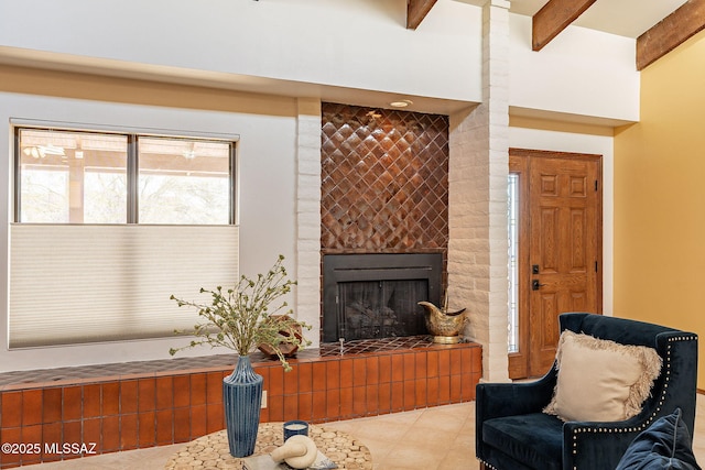 living area with a fireplace, beamed ceiling, and light tile patterned flooring