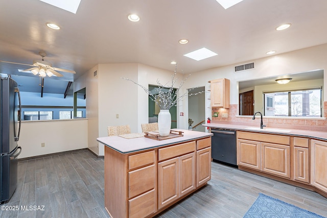 kitchen featuring a skylight, visible vents, dishwashing machine, freestanding refrigerator, and a sink