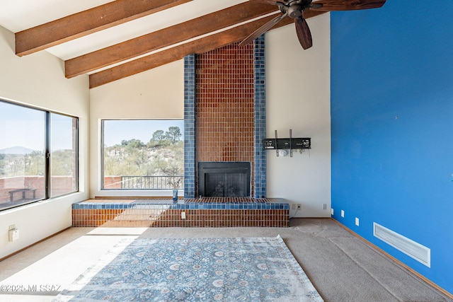 unfurnished living room with visible vents, beamed ceiling, carpet, a fireplace, and high vaulted ceiling