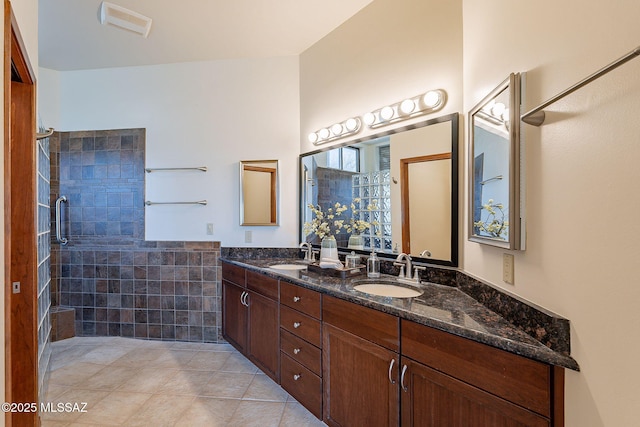 bathroom with tile patterned floors, a sink, a tile shower, and double vanity