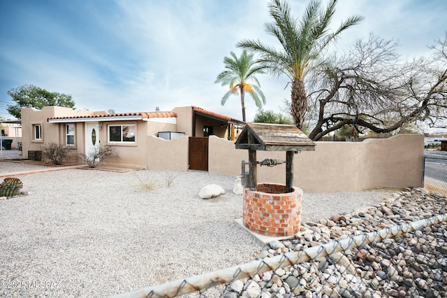 southwest-style home featuring central AC unit, a tile roof, fence, and stucco siding