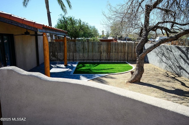 view of yard featuring a patio area, a fenced backyard, and a ceiling fan