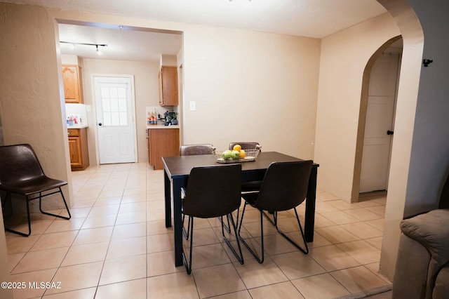 dining room with arched walkways and light tile patterned floors