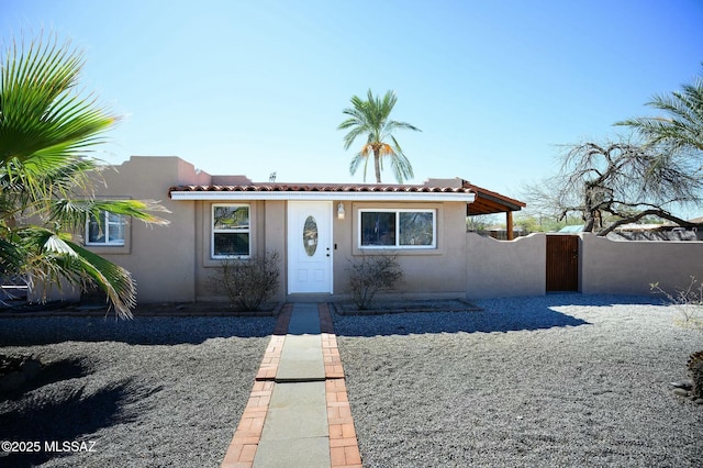 view of front facade featuring a gate, a tile roof, and stucco siding