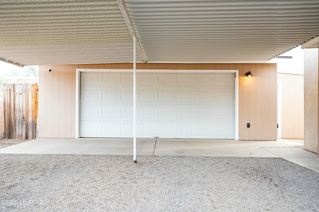 garage with gravel driveway and fence