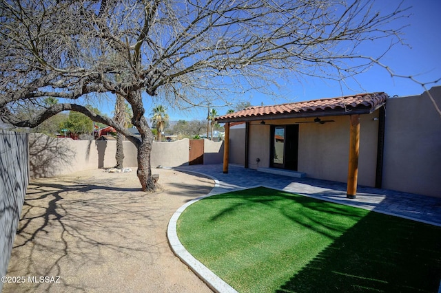 view of yard with a patio area, a fenced backyard, and a ceiling fan