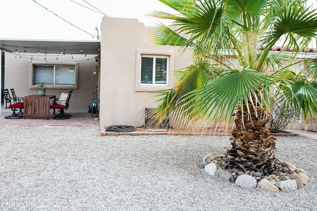 view of side of home with outdoor dining space, a patio, and stucco siding