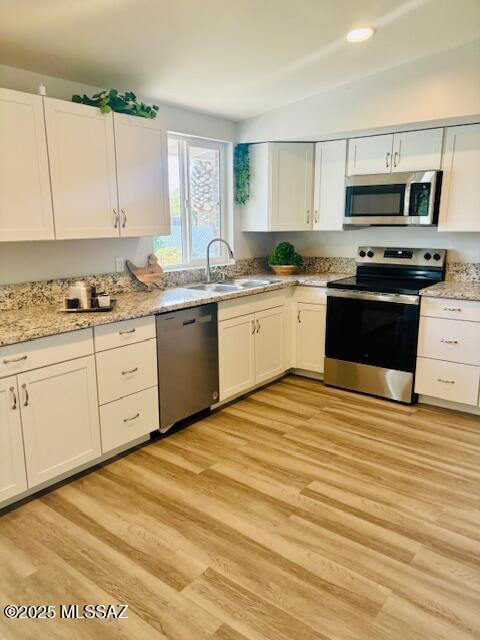 kitchen with appliances with stainless steel finishes, a sink, and white cabinetry