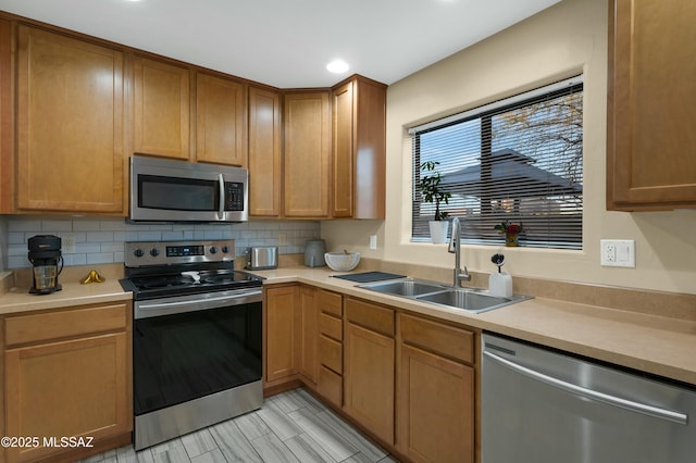 kitchen featuring stainless steel appliances, recessed lighting, light countertops, decorative backsplash, and a sink