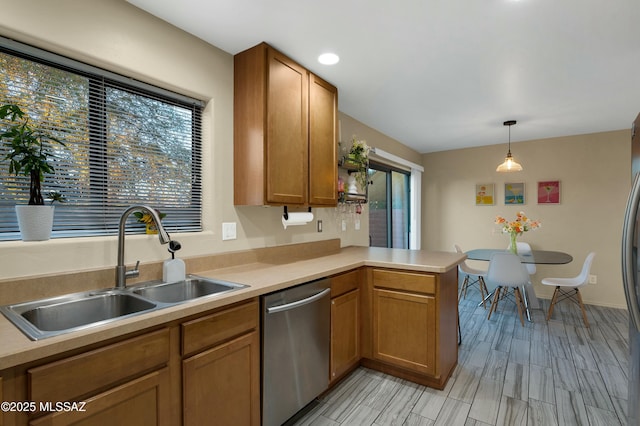 kitchen with a peninsula, a sink, light countertops, brown cabinets, and dishwasher