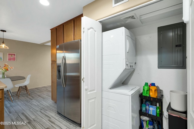 laundry area featuring baseboards, electric panel, visible vents, and stacked washing maching and dryer