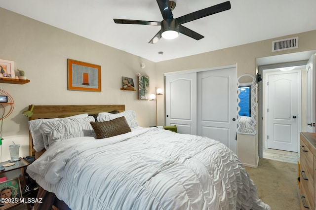 bedroom featuring a ceiling fan, visible vents, a closet, and light colored carpet