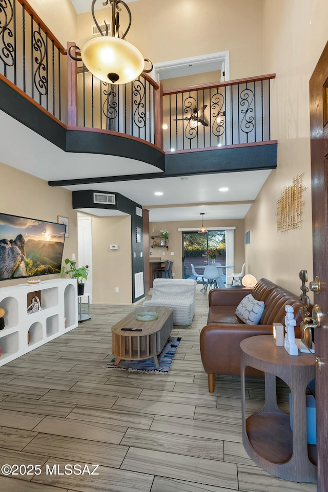 living area featuring wood tiled floor, a high ceiling, and visible vents