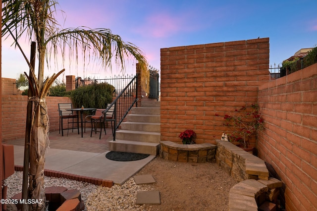 patio terrace at dusk featuring fence and outdoor dining space