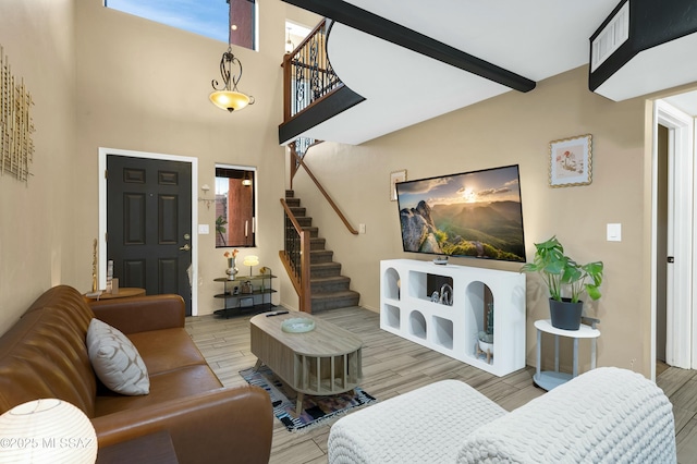 living room with a healthy amount of sunlight, stairs, beamed ceiling, and wood finish floors