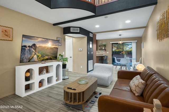 living area with wood finish floors, beam ceiling, recessed lighting, visible vents, and baseboards