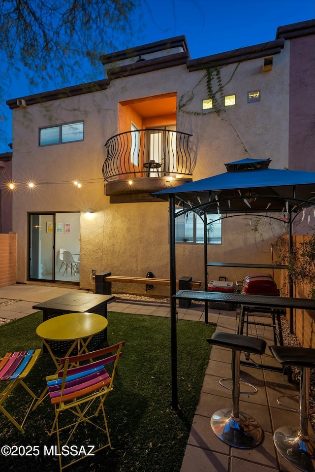 rear view of property featuring a patio area, a balcony, and stucco siding