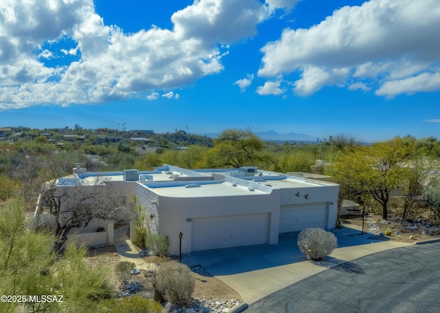 view of front of property with an attached garage, a mountain view, concrete driveway, and stucco siding