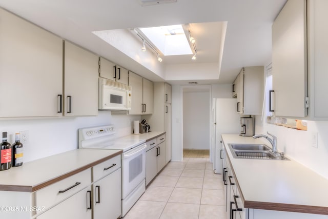 kitchen featuring light countertops, white appliances, a skylight, and a sink