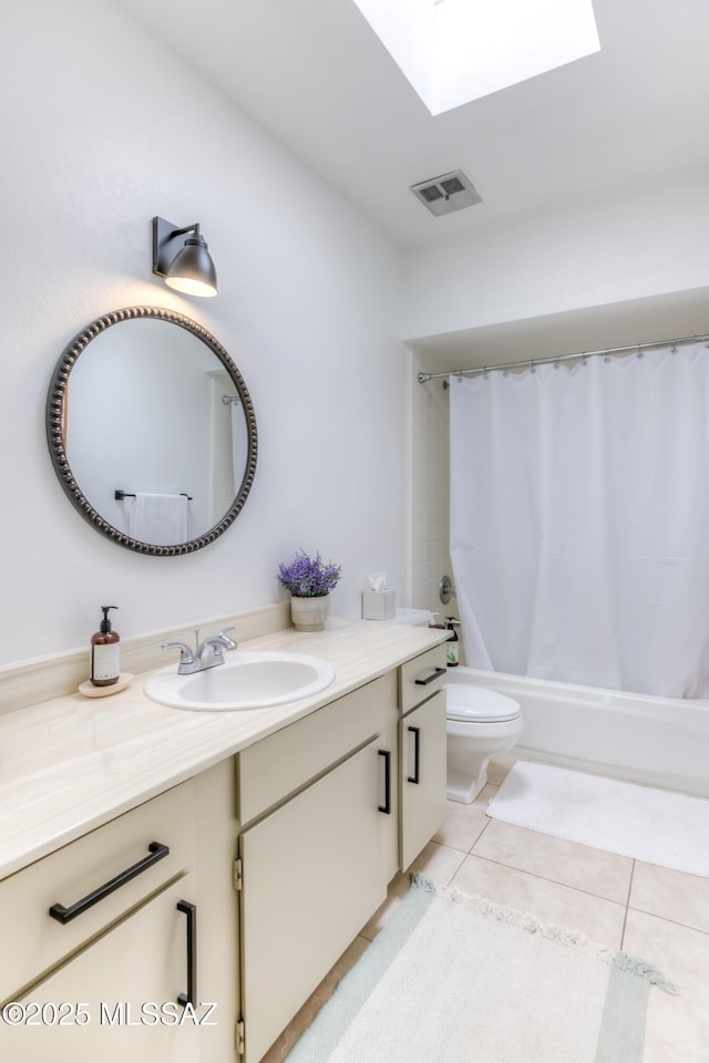 bathroom with a skylight, visible vents, toilet, vanity, and tile patterned floors