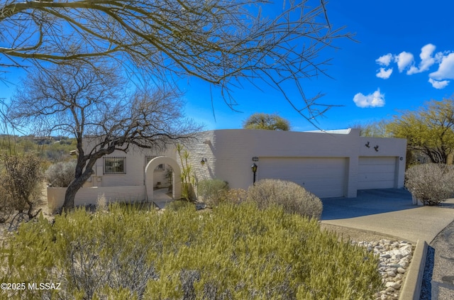 pueblo-style home with an attached garage and stucco siding