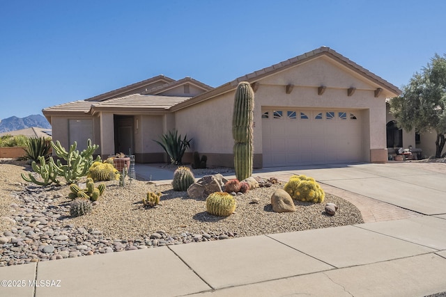 view of front of house featuring a garage, concrete driveway, a tile roof, and stucco siding