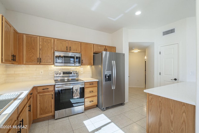 kitchen with appliances with stainless steel finishes, visible vents, light tile patterned flooring, and backsplash