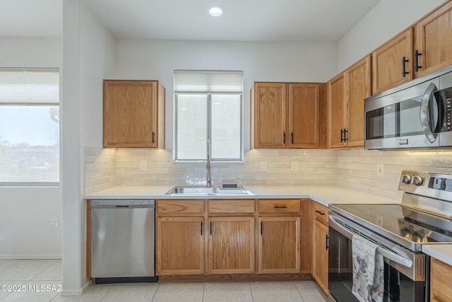 kitchen featuring decorative backsplash, stainless steel appliances, a sink, and light countertops