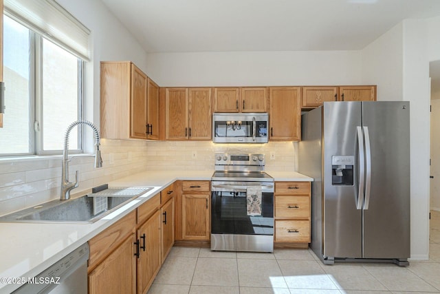 kitchen with stainless steel appliances, backsplash, a sink, and light countertops