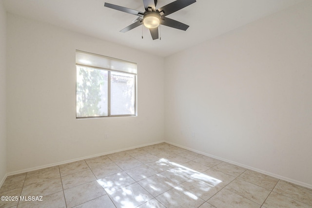 spare room featuring light tile patterned floors, ceiling fan, and baseboards