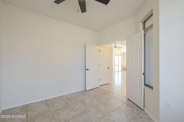 empty room with light tile patterned floors, ceiling fan, and baseboards