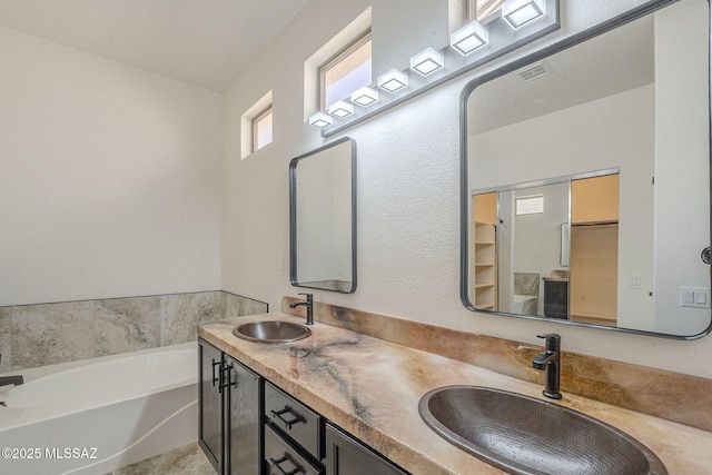 bathroom with a garden tub, double vanity, a sink, and visible vents