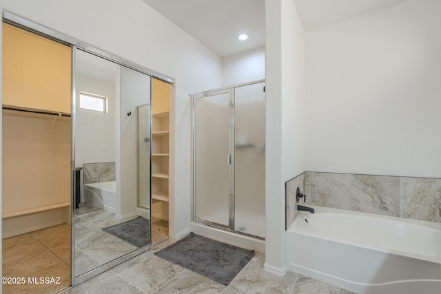 bathroom featuring tile patterned flooring, a garden tub, a spacious closet, and a shower stall