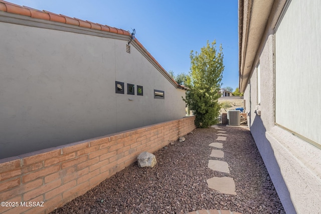 view of side of property with fence, cooling unit, and stucco siding