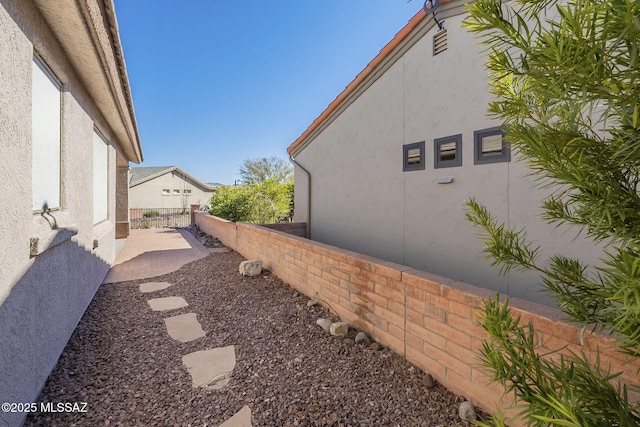 view of side of home with fence and stucco siding