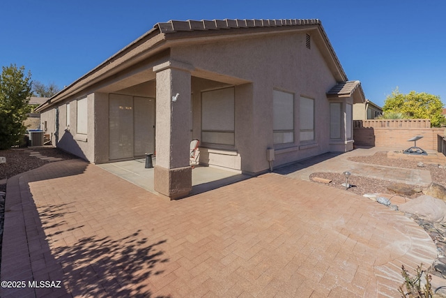 back of property with a patio, central AC unit, fence, a tiled roof, and stucco siding