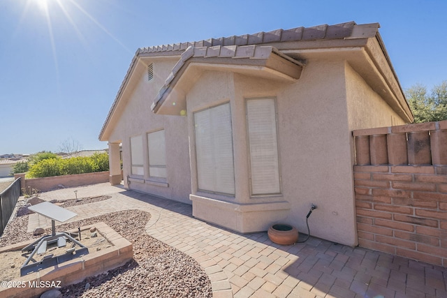 view of property exterior with stucco siding, a fenced backyard, and a patio