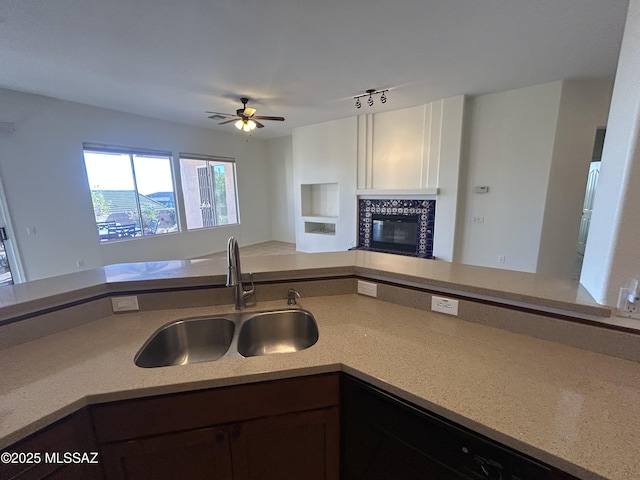 kitchen featuring dark brown cabinetry, a tile fireplace, open floor plan, light countertops, and a sink