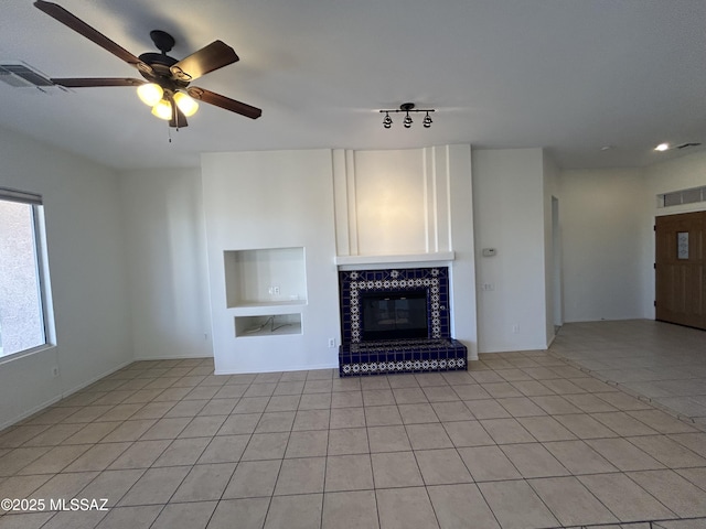 unfurnished living room with light tile patterned floors, a tile fireplace, visible vents, built in features, and a ceiling fan