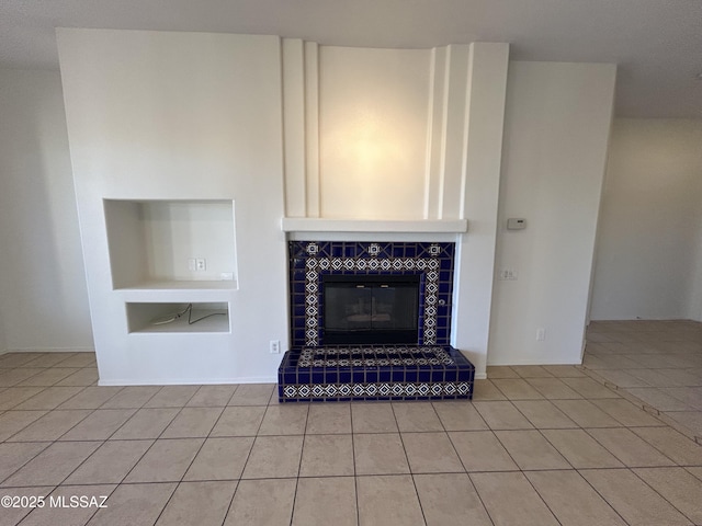 unfurnished living room featuring built in shelves, a fireplace, and light tile patterned flooring