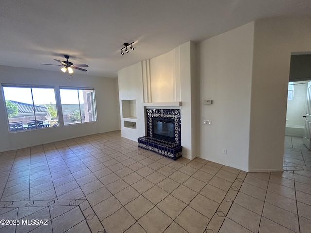 unfurnished living room featuring a ceiling fan, a glass covered fireplace, built in shelves, and light tile patterned floors