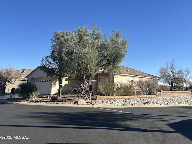 view of front of home featuring an attached garage, a tile roof, and stucco siding