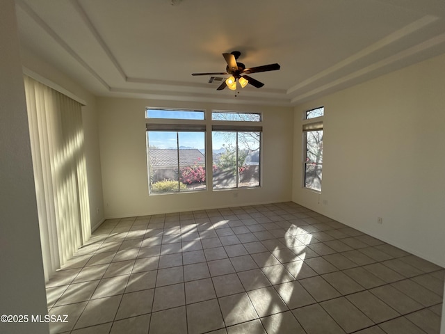 spare room featuring light tile patterned floors, ceiling fan, visible vents, and a tray ceiling