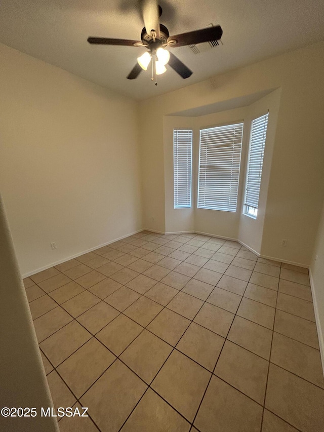 empty room featuring ceiling fan, baseboards, and light tile patterned flooring