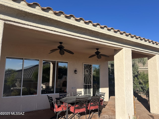 view of patio featuring a ceiling fan, outdoor dining space, and fence