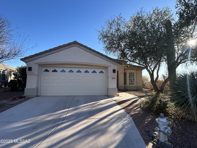 ranch-style home with a garage, driveway, a tile roof, and stucco siding